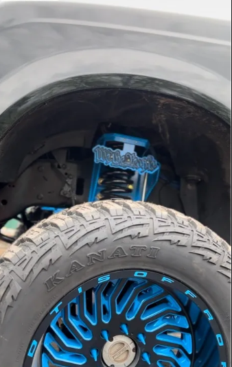 Close-up of custom blue suspension kit, Kanati off-road tire, and blue alloy wheel on truck