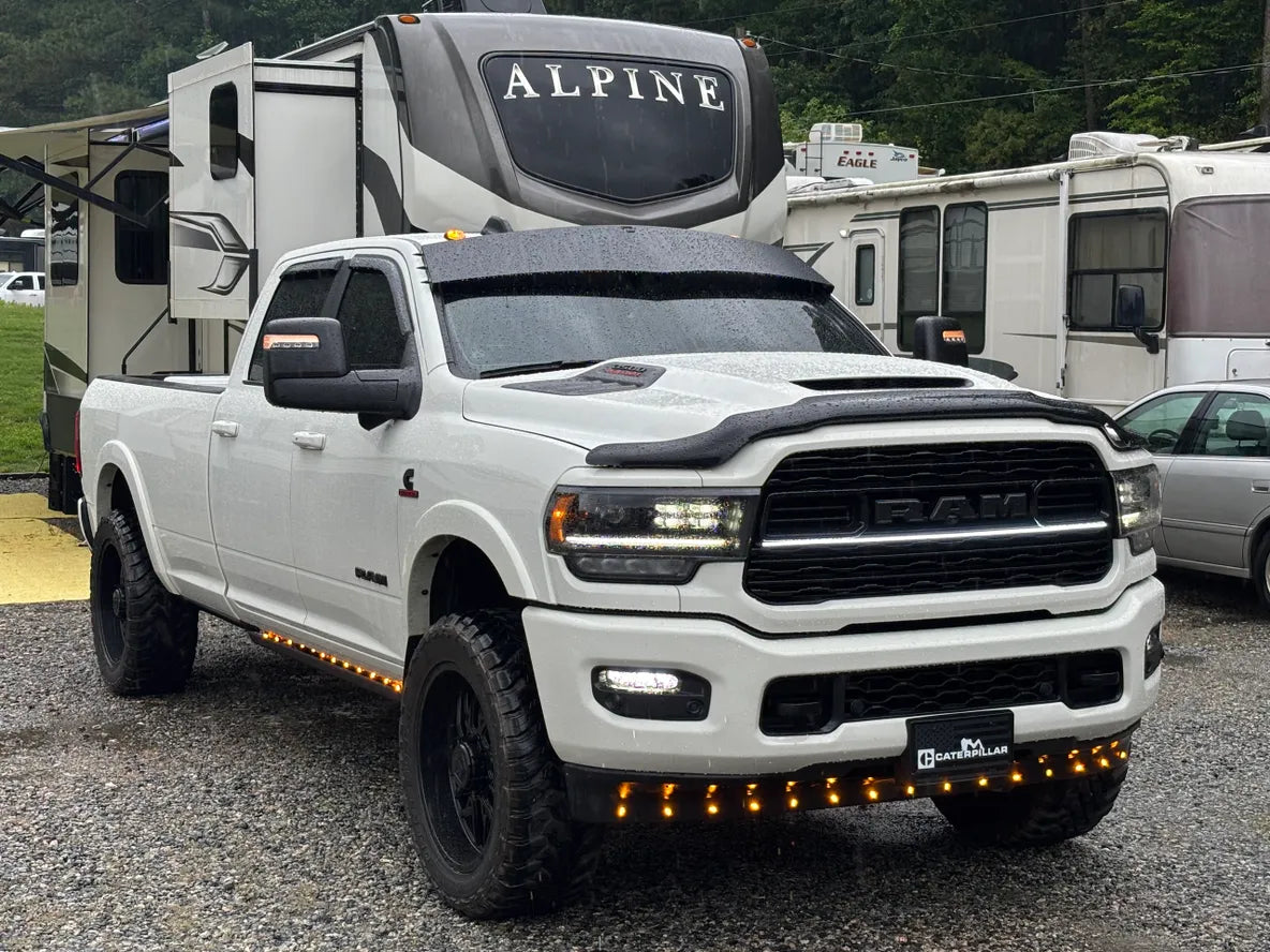 White RAM pickup truck with lift kit, off-road tires, and LED accent lights in RV park