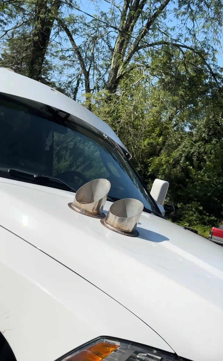 Dual hood exhaust vents on a white pickup truck parked outdoors in sunlight