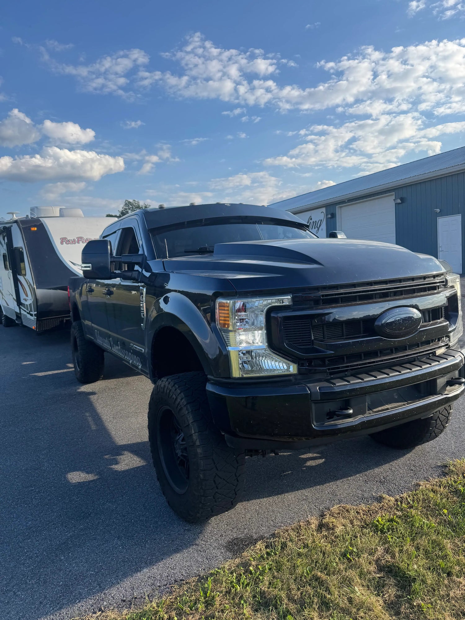 Black Ford truck towing RV under sunny sky