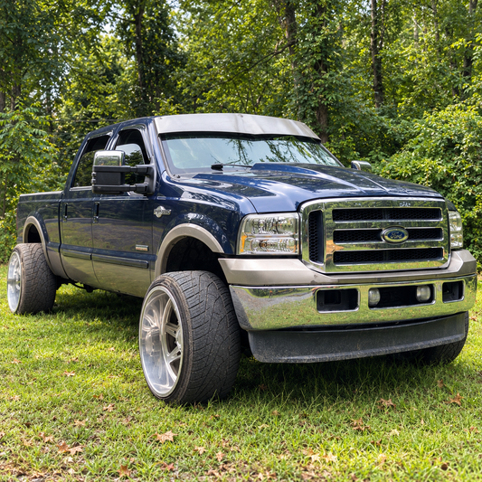 Dark blue Ford Super Duty with a raw-finish TRUBLU Fab 5-inch V drop visor, front three-quarter view