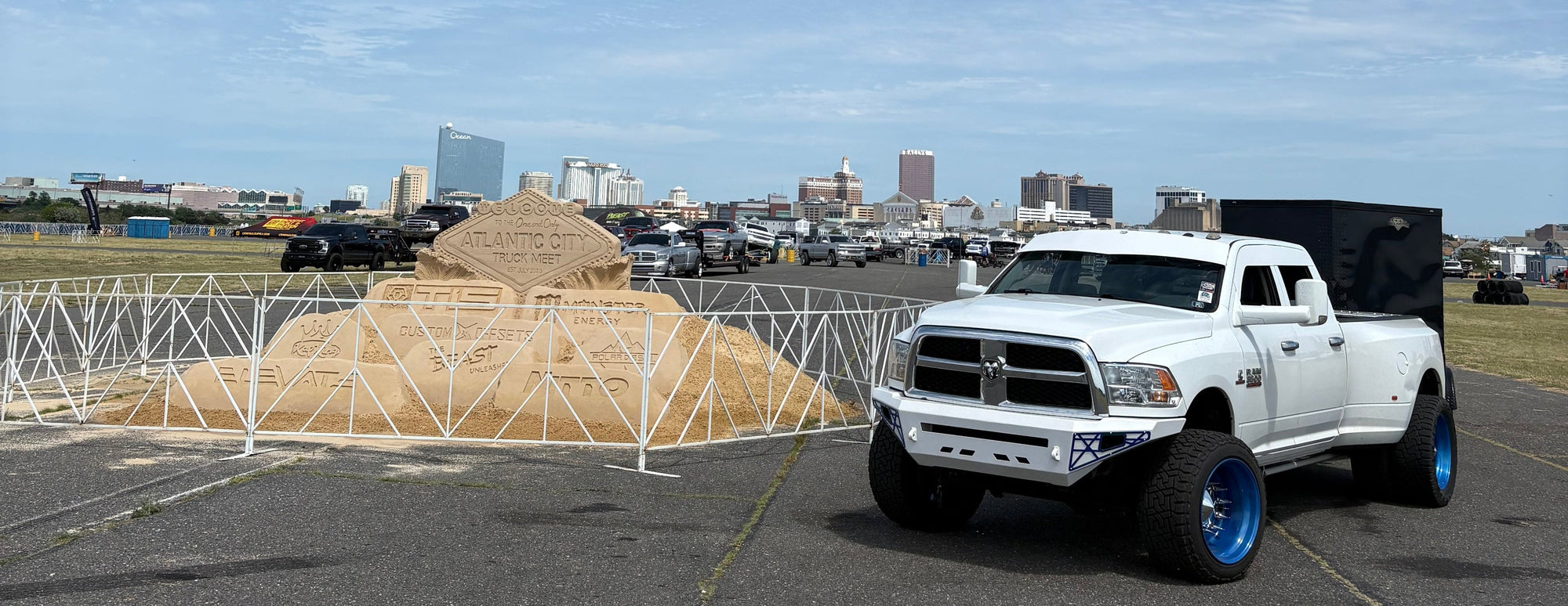 White lifted Ram truck with blue rims at Atlantic City Truck Meet, sand sculpture backdrop