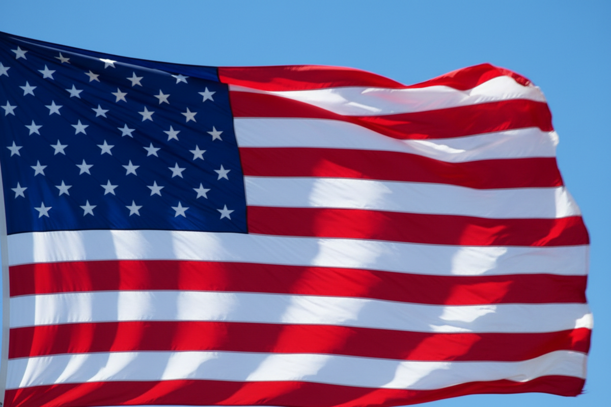 An American flag waving in the wind against a clear blue sky.