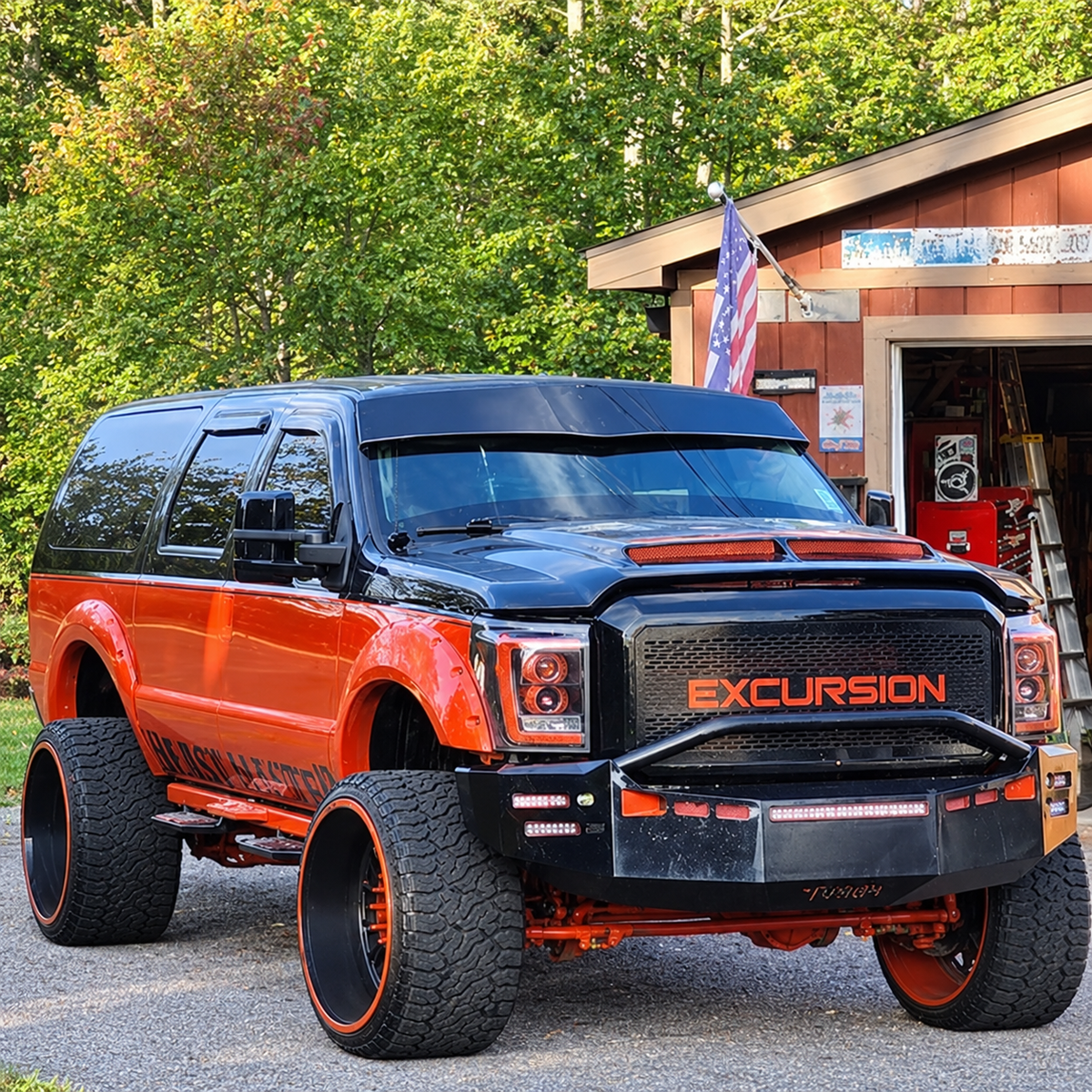 Custom orange-and-black Ford Excursion with a TRUBLU Fab V drop visor, front three-quarter view