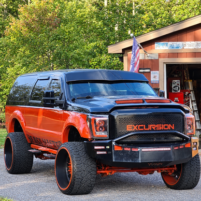 Custom orange-and-black Ford Excursion with a TRUBLU Fab V drop visor, front three-quarter view