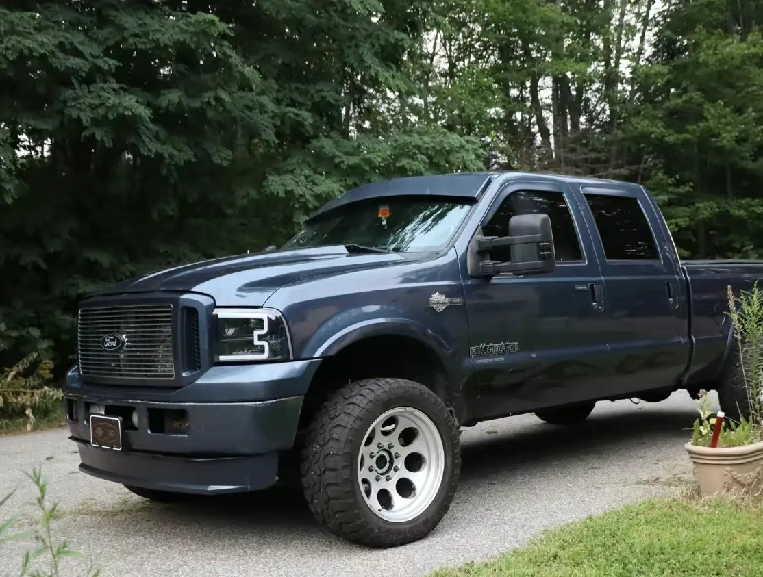 Blue Ford Super Duty pickup truck parked outdoors on a driveway surrounded by trees