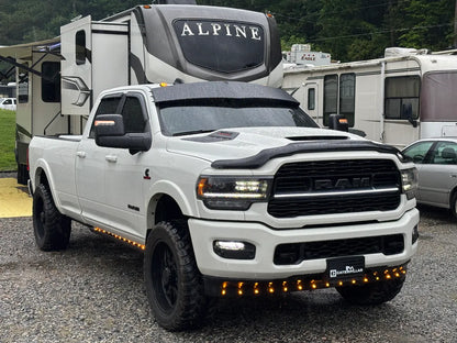 White RAM pickup truck with lift kit, off-road tires, and LED accent lights in RV park