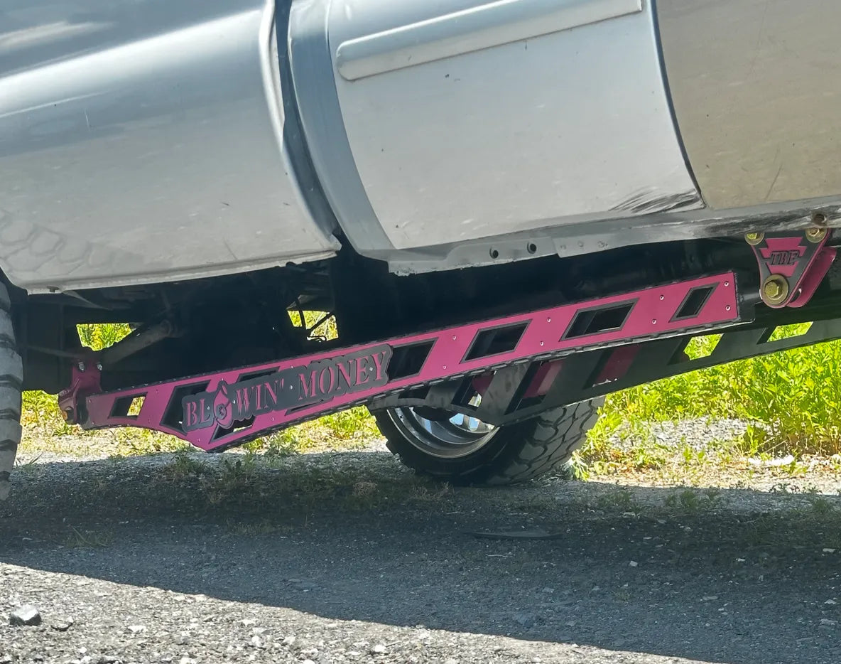 Pink custom truck suspension traction bar with 'Blowin' Money' text on lifted pickup