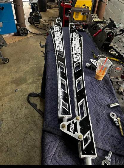 Custom black and white metal rock sliders with cutout design on workshop table