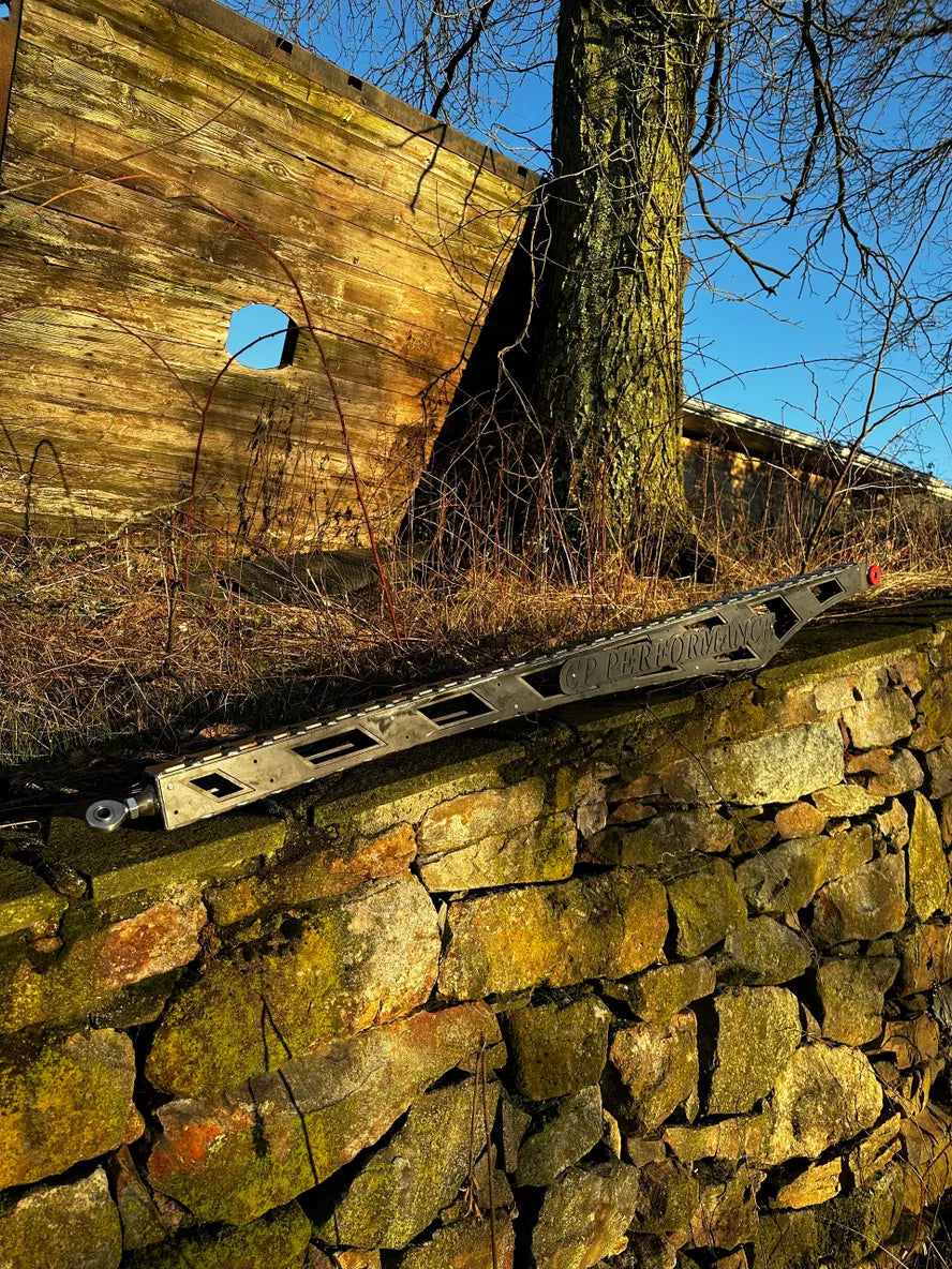 Metal car suspension component on mossy stone wall with rustic wood structure and tree