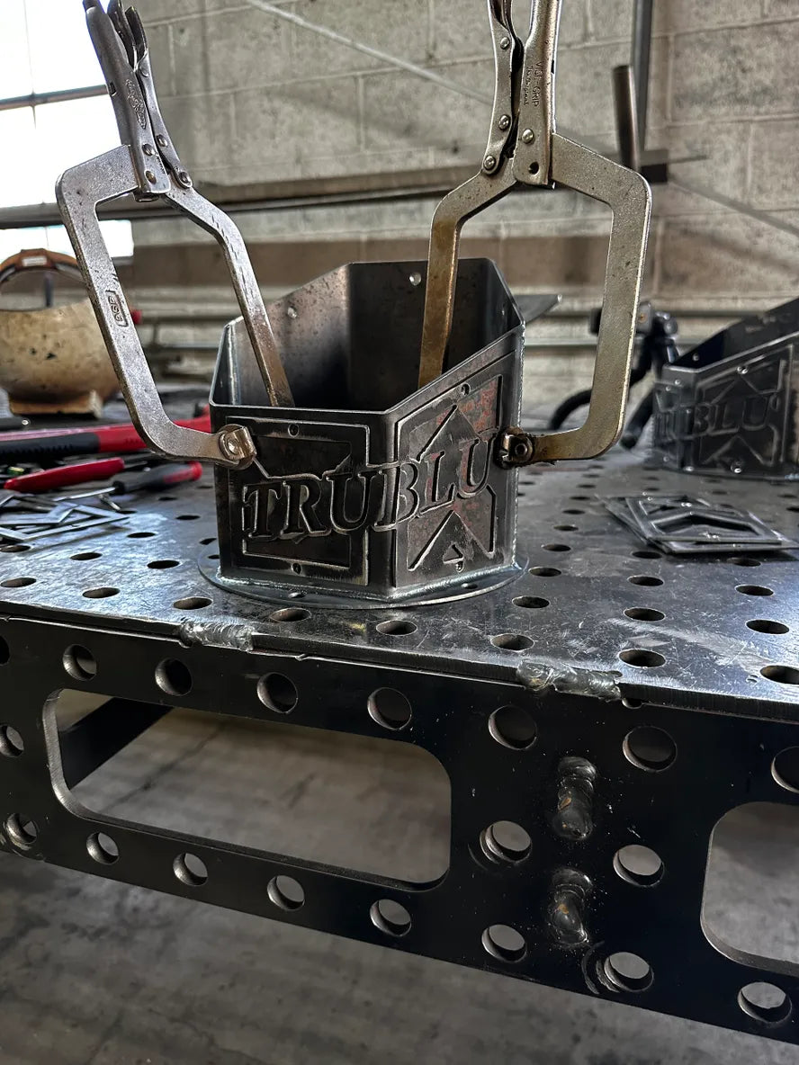 Metal fabrication project with clamps securing welded steel pieces on workshop table