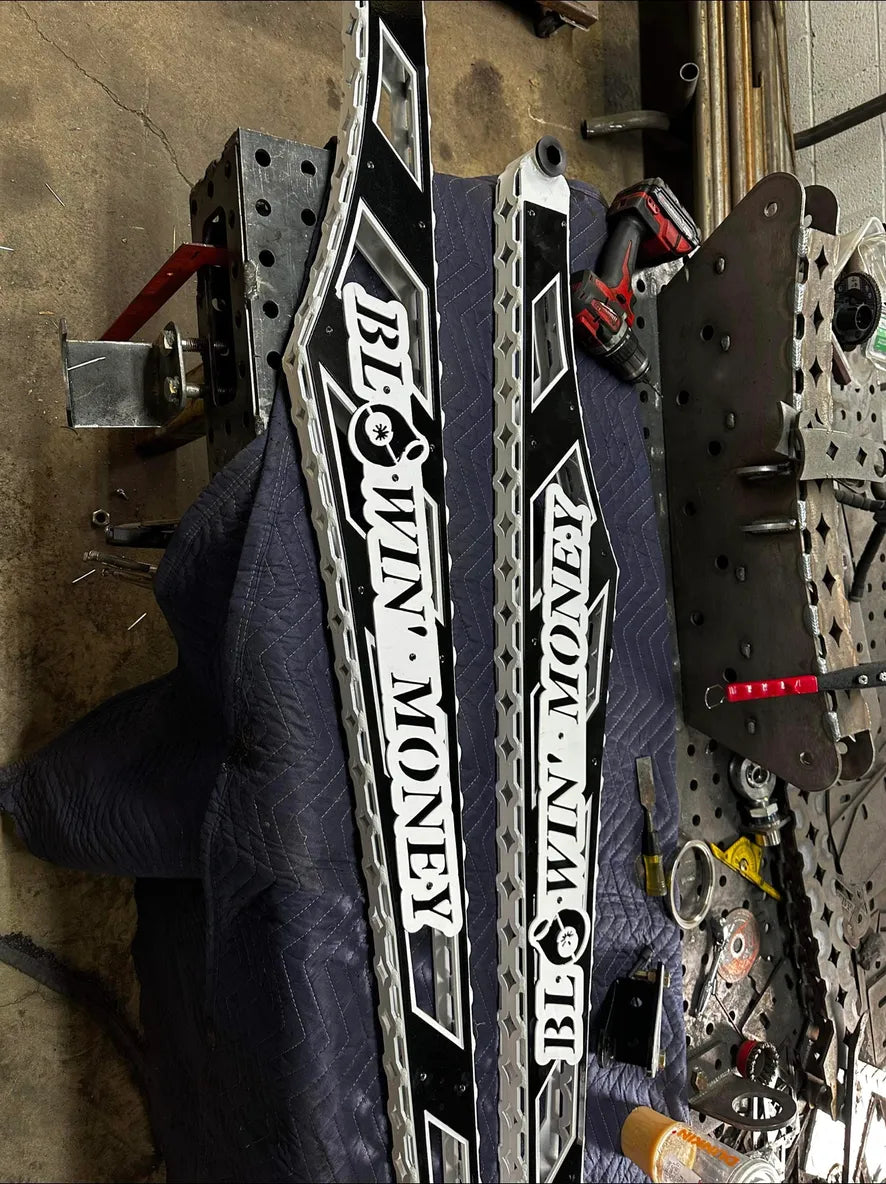 Custom fabricated metal parts with 'BLOWIN MONEY' text in a workshop setting