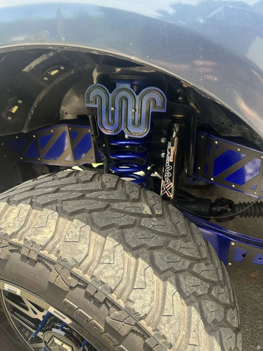 Close-up of custom truck suspension with blue coil spring and off-road tire