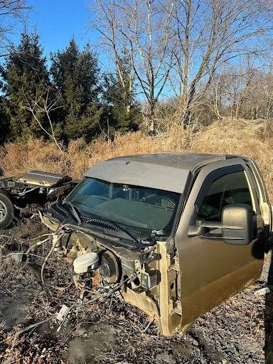 Disassembled truck cab without front end parts in an outdoor salvage yard.