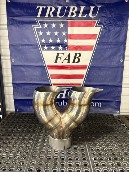 Stainless steel exhaust Y-pipe with welds on a perforated metal workbench