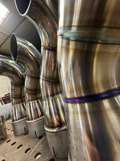 Close-up of welded stainless steel exhaust pipes on a workshop table