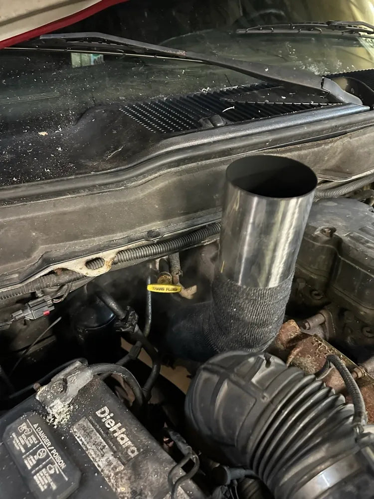 Custom exhaust pipe with heat wrap installed in truck engine bay, close-up view