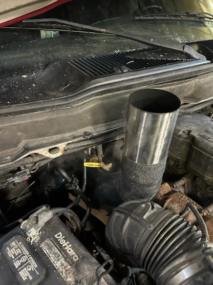 Custom exhaust pipe with heat wrap installed in truck engine bay, close-up view