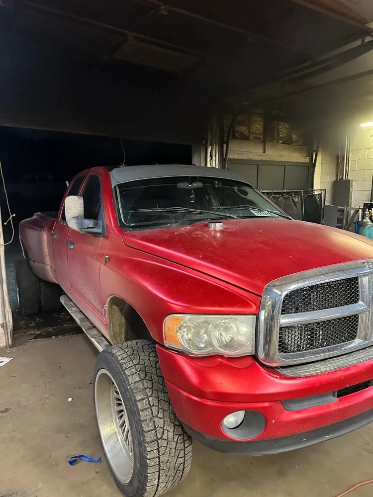 Red custom lifted truck with oversized wheels parked in an automotive workshop