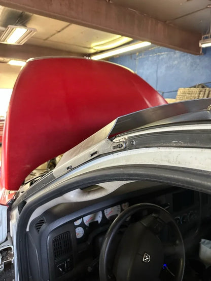 Custom metal A-pillar trim installed on Dodge truck with red hood open in auto shop