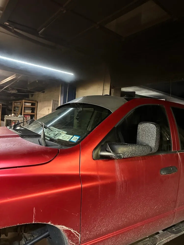 Red pickup truck with dusty exterior in a workshop garage setting