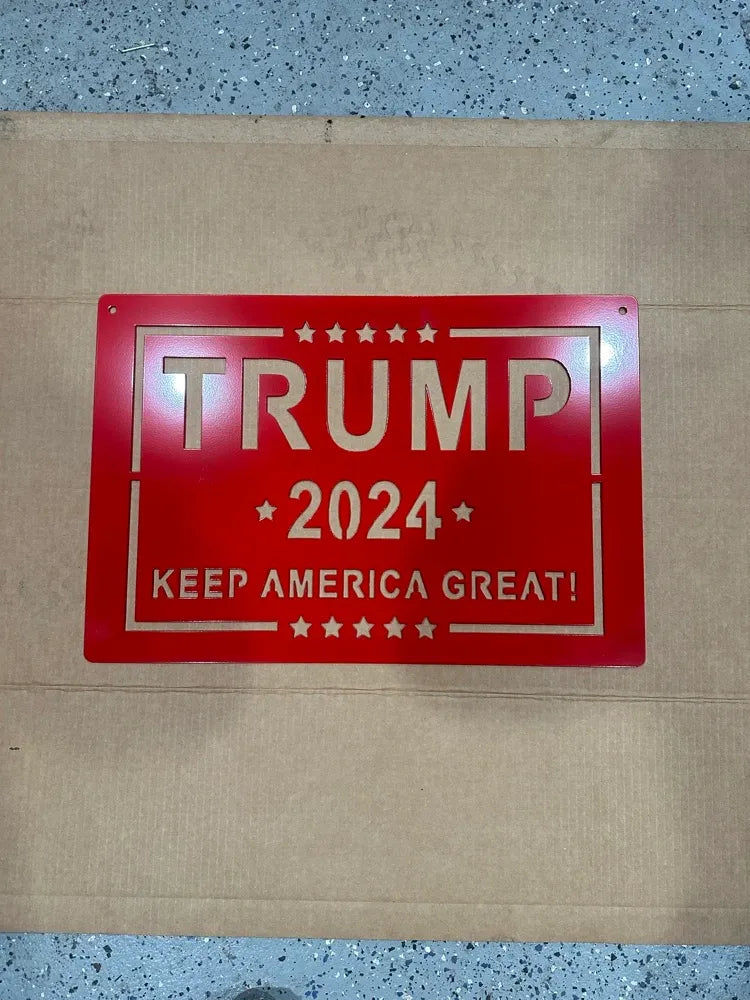 Red metal Trump 2024 Keep America Great wall sign with stars, displayed on cardboard.