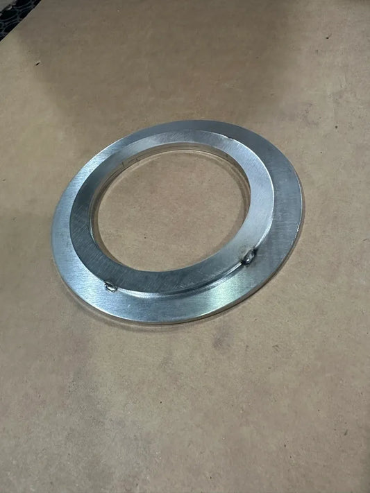 CNC machined aluminum ring part on a workshop table, showing metal fabrication detail