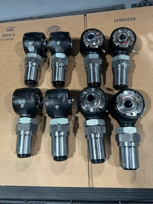 Nine heavy-duty steel rod end heim joints with black housing and silver threaded shank on cardboard.