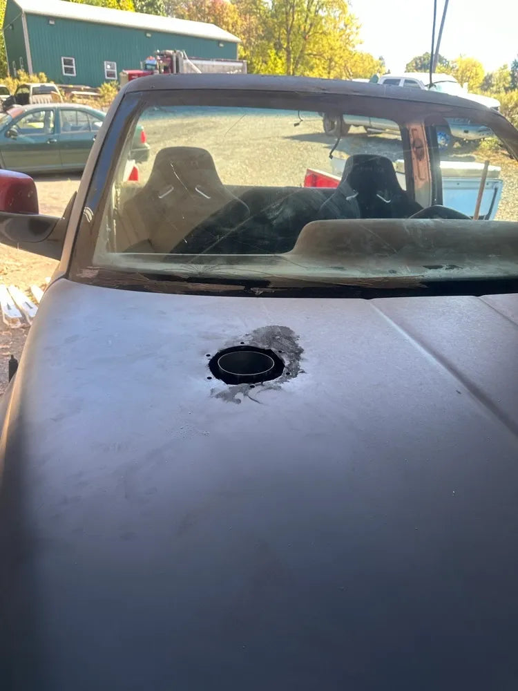 Car hood with freshly cut circular hole for hood stack exhaust, convertible interior visible