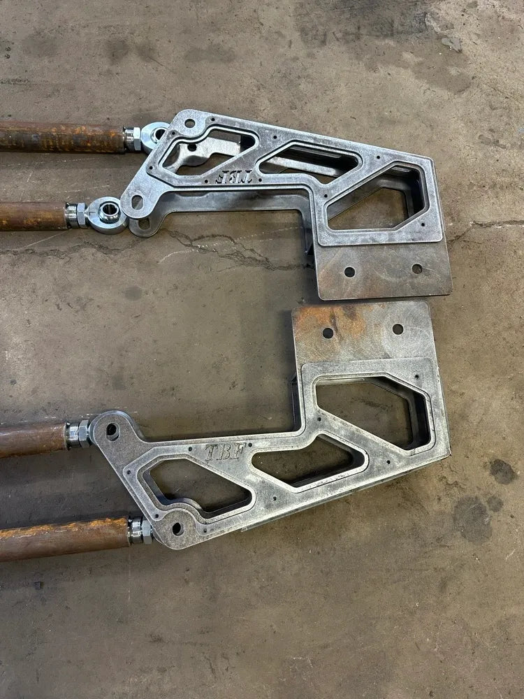 Pair of heavy-duty metal suspension brackets with welded joints on a concrete floor