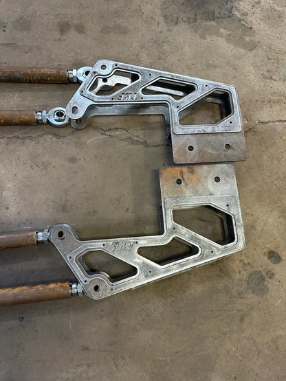 Pair of heavy-duty metal suspension brackets with welded joints on a concrete floor
