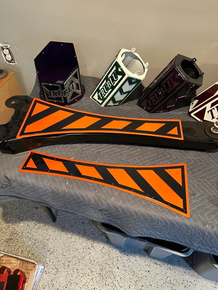 Custom metal automotive parts with orange and black hazard stripes and TRUBLU logo covers