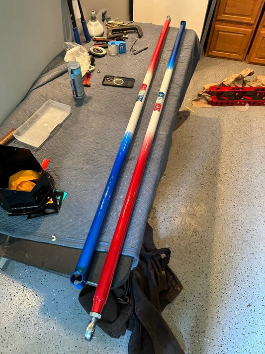 Two heavy-duty adjustable metal rods painted red, white, and blue on a workshop table
