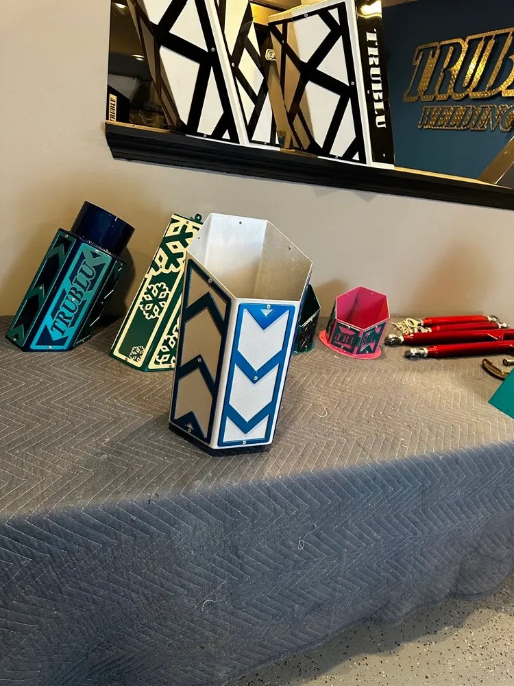 Geometric metal desk organizers with colorful patterns on display table in workshop