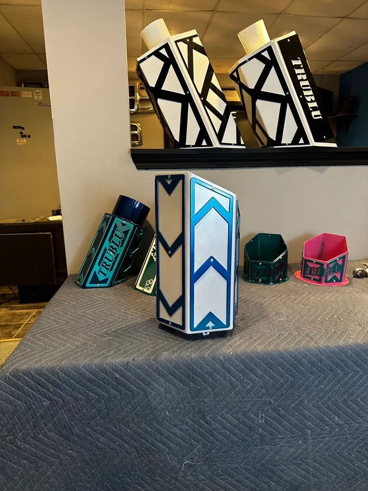 Geometric metal custom vases and containers in various colors displayed on a table indoors