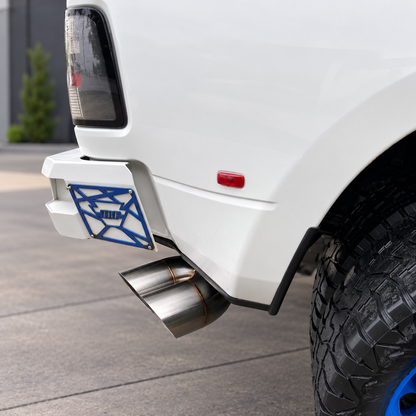 Stainless steel dual mitre exhaust tip installed below the rear corner of a white truck